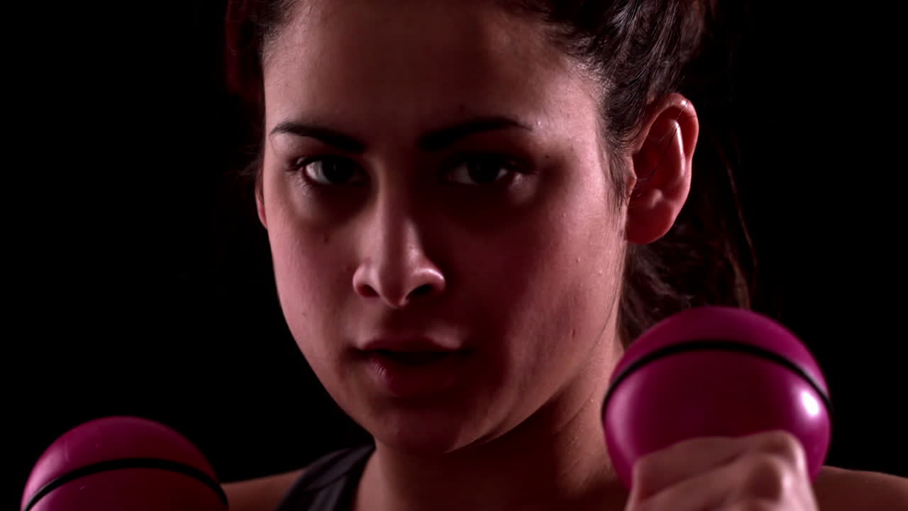 mujer en forma enfocada golpeando con pesas