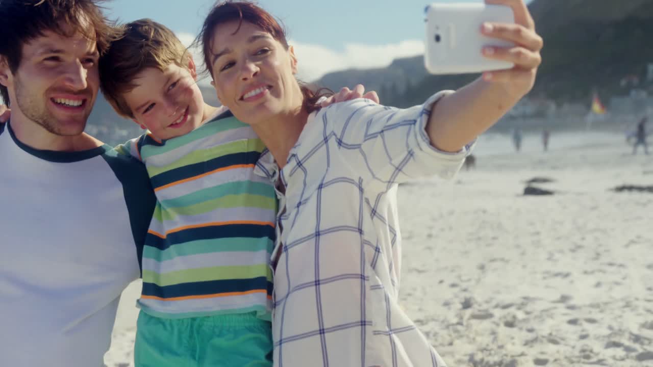 familia feliz tomando una selfie desde el teléfono móvil en la playa