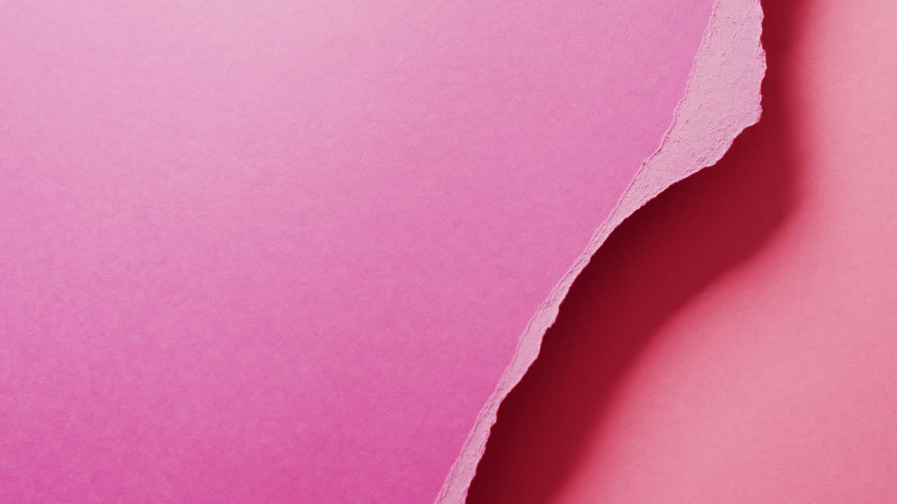 Video in primo piano di pezzi strappati di carta rosa con spazio per il testo come sfondo.