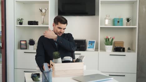 el retrato muestra a un hombre joven, guapo y serio que ha llegado a un nuevo lugar de trabajo y está desempaquetando sus cosas sobre el escritorio, vestido con traje de negocios y expresando felicidad por su ascenso.