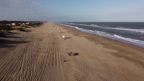vista aérea que muestra el estacionamiento familiar en la playa de arena durante las vacaciones y disfruta de las vibraciones del océano durante la puesta de sol
