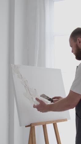 male artist paints a picture with oil paints artist while working in the studio