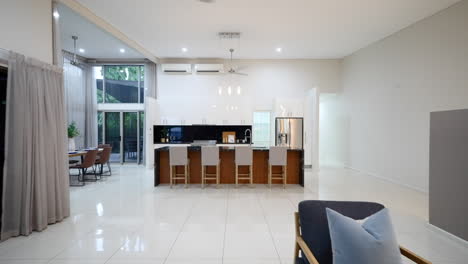 huge modern tiled kitchen pullback to lounge area from grey bar stool seating