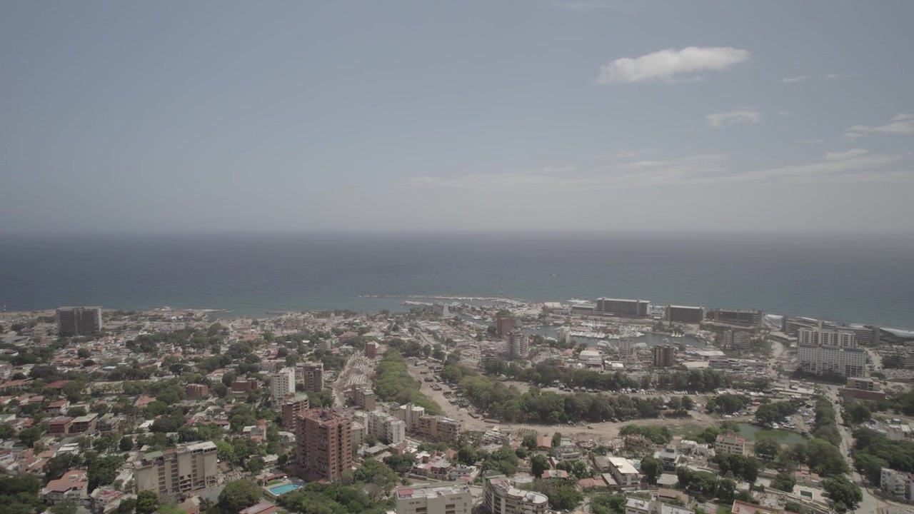 Luftaufnahme zeigt die weitreichenden städtischen und strukturellen Auswirkungen in La Guaira, Venezuela, nach dem massiven Erdbeben im Juni 2026, mit karibischem Meer im Hintergrund. Video 4k Dlog
