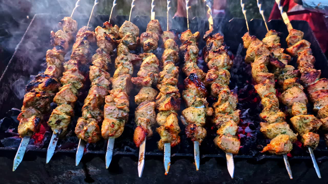 Grilled chicken skewers over hot coals with smoke rising during barbecue