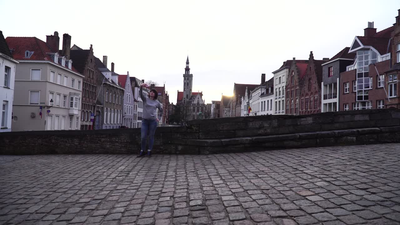 una turista hace un selfie en un teléfono inteligente en un fondo de la ciudad de bruges, bélgica