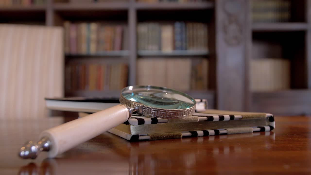 Archaeologist's Magnifying Glass on an Old Book in a Office with a Library in the Background