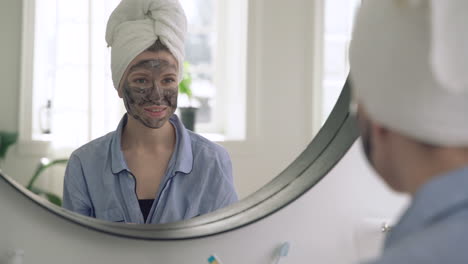 woman with facial mask looking to the mirror