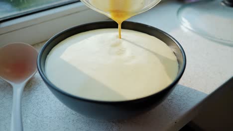 creamy pancake batter slowly poured into bowl in bright, cozy kitchen corner