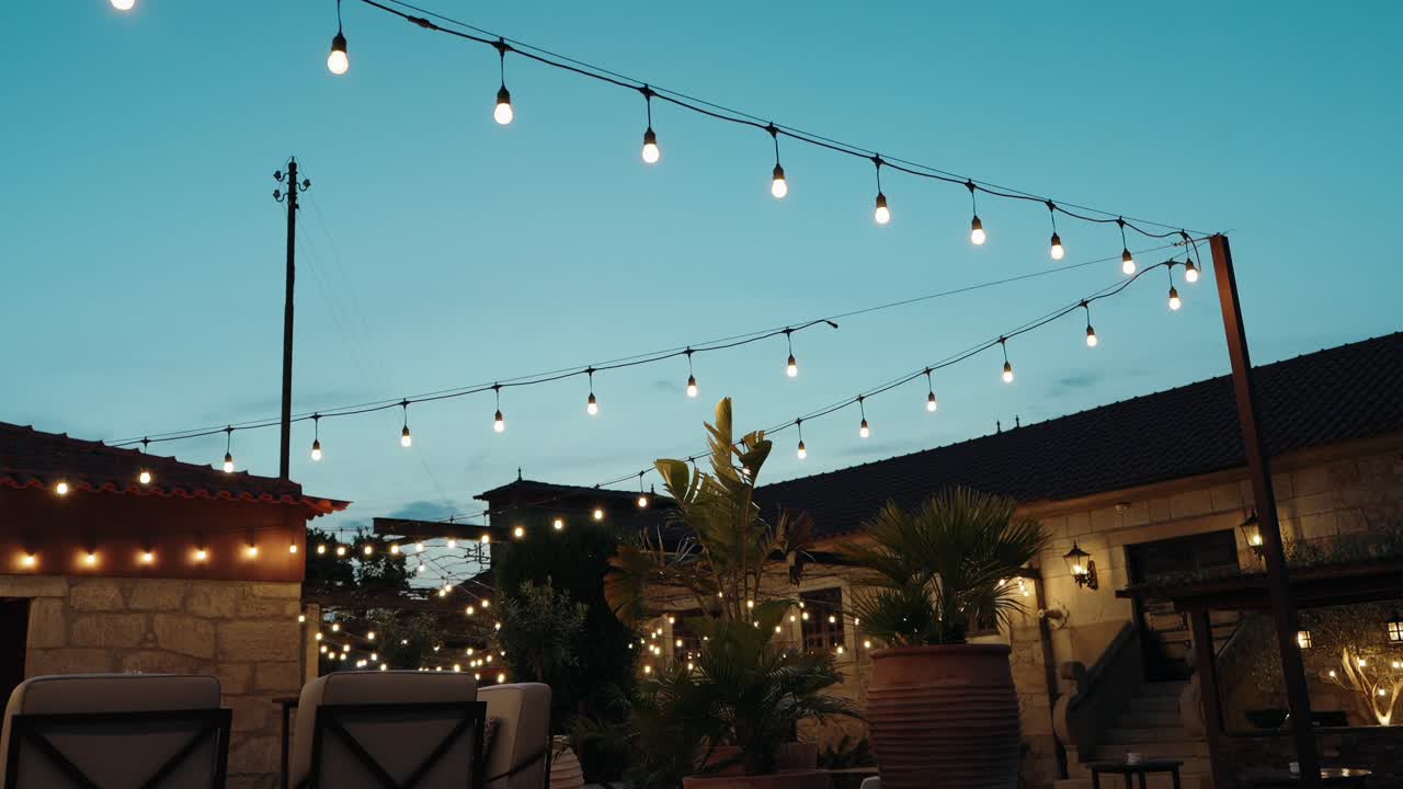 cozy outdoor courtyard lit by hanging bulbs and warm lights during twilight