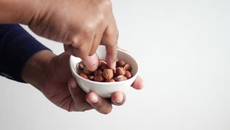hand holding a bowl of hazelnuts
