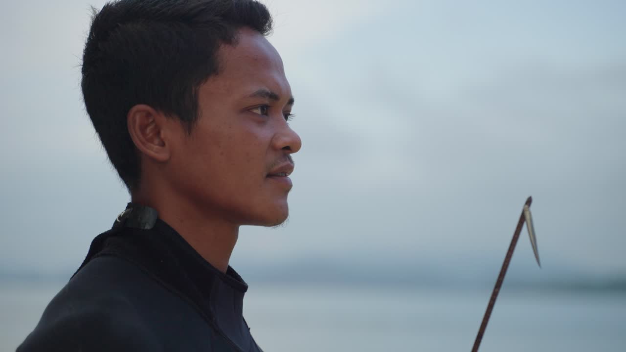 스피어 시의 얼굴이 스피어건을 들고 배경에 초점을 맞추지 않은 바다를 바라보고 있는 근접한 측면