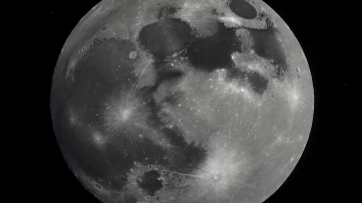 Telescópio capturando o lado próximo da Lua, oscilando levemente no espaço e revelando maria e raios de crateras.