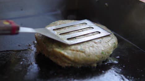 close up of chief cook pushing down burger to the grill to be cooked thoroughly in slowmotion