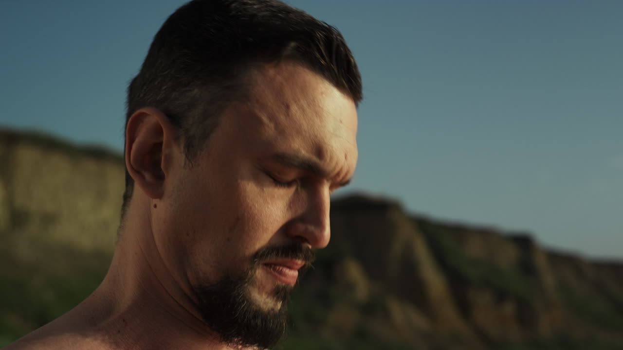 잔인한 운동 선수가 목을 따뜻하게 하고 자연에서 가까이서 훈련합니다. 남자가 머리를 구부리고 있습니다.