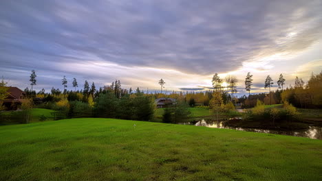 Clouds-move-over-country-landscape,-lake,-rural-properties-and-forest,-blurred-timelapse-video