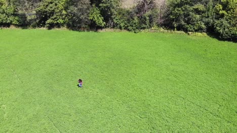 tracking shot of a young woman running through an open green field having the time of her life