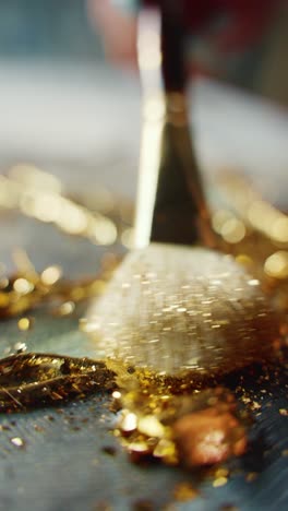 applying gold glitter to a painting