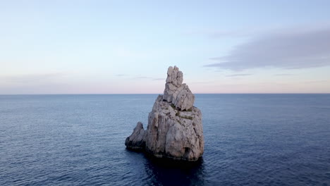 Aerial-smooth-dolly-out-shot-of-Ibiza's-iconic-rock-Benirrás-just-before-the-sunrise-in-4K-ProRes