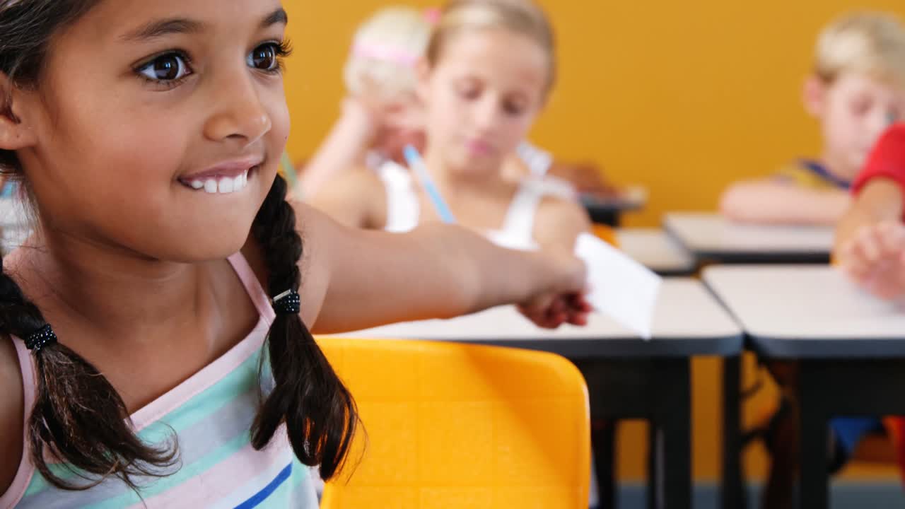 Schoolgirl giving chit to her friends in classroom