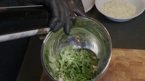 Oil-is-poured-delicately-into-a-bowl-of-fresh-arugula,-enhancing-the-salad's-flavor