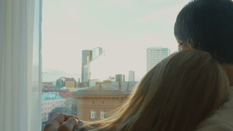 young couple enjoying city view through the window