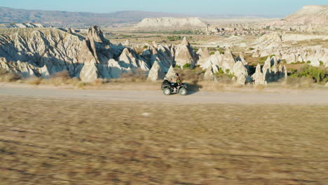 Woman-on-Quad-drives-past-Love-valley-with-fairy-chimneys-in-the-background