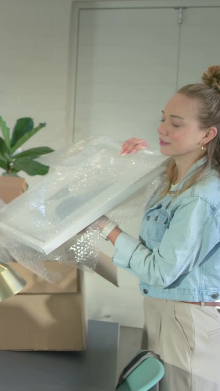 Vertical video: As man shifting box pair unpacking at table woman denim unwrapping brass lamp