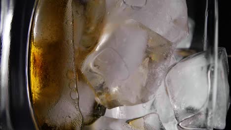 primer plano refrescante de coque vertiendo en vidrio con cubitos de hielo, disparo vertical