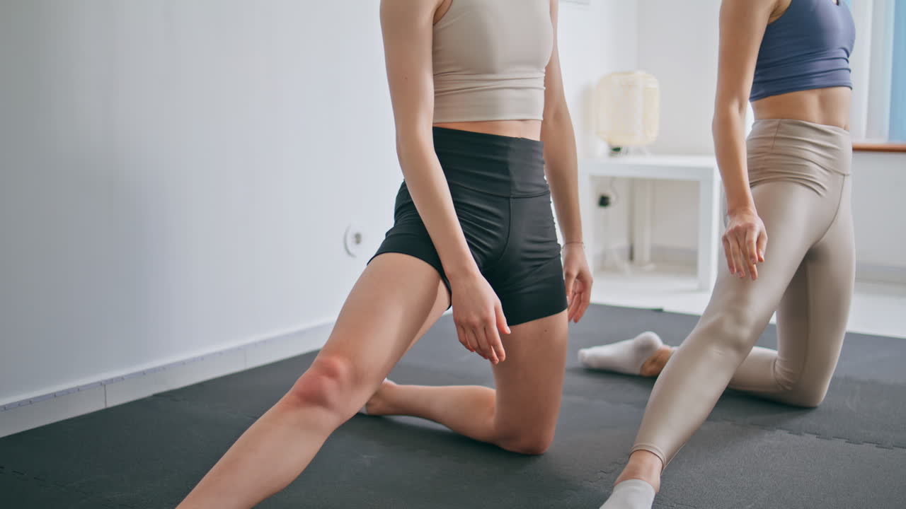 Flexible ladies bending body foot indoors. Slim girls stretching waist muscles