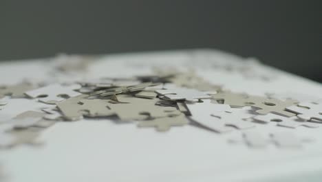 white and gray puzzle pieces laying randomly on a white surface with a dark background