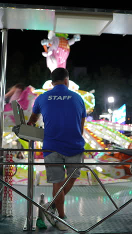 fairground staff operating an amusement park ride at night