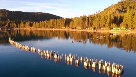 evening sunset drone aerial over glenbrook, lake tahoe, nevada, with old pier pilings coming out of calm water