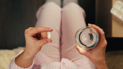 mujer tomando medicamentos en la cama