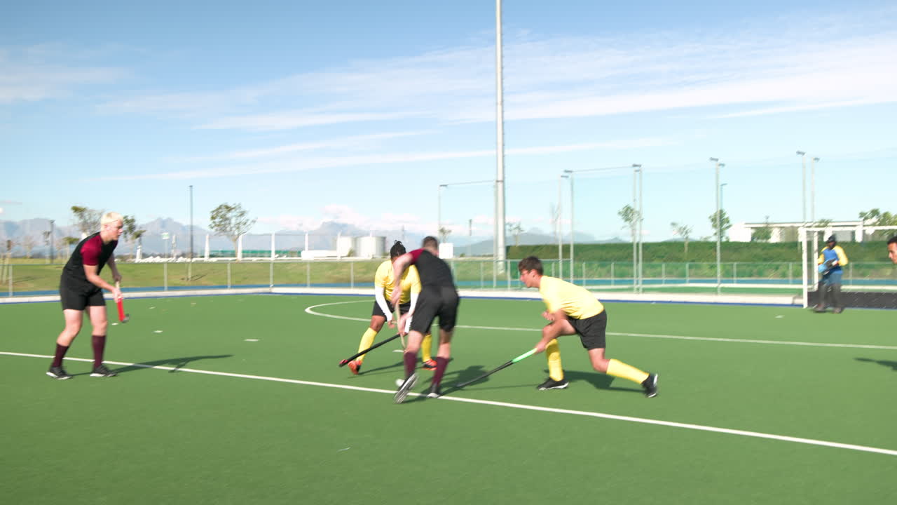 Playing field hockey, male players in action on outdoor field, competing intensely