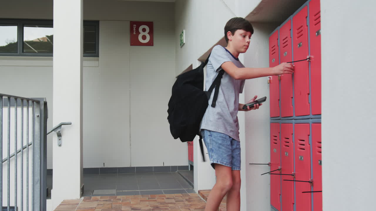 At school, boy with backpack opening locker, preparing for class
