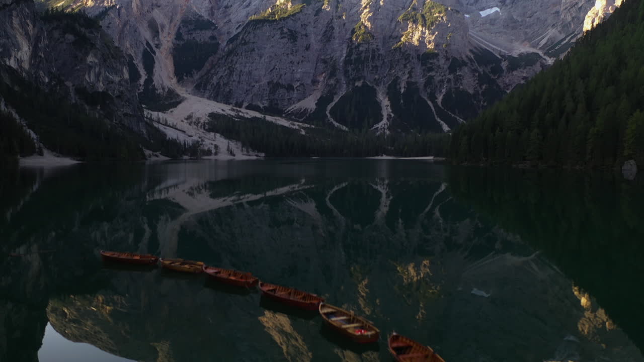 volando sobre botes de remos en un lago que se refleja revelando los imponentes alpinos del tirol - vista aérea