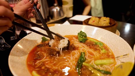 person eating noodles with chopsticks in melbourne