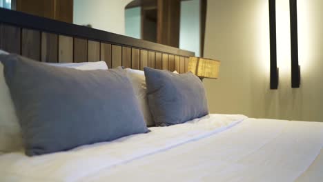 white linens, fluffy pillows and wooden headboard create a cozy and inviting atmosphere in a modern hotel room, perfect for a relaxing stay, slow motion reveal