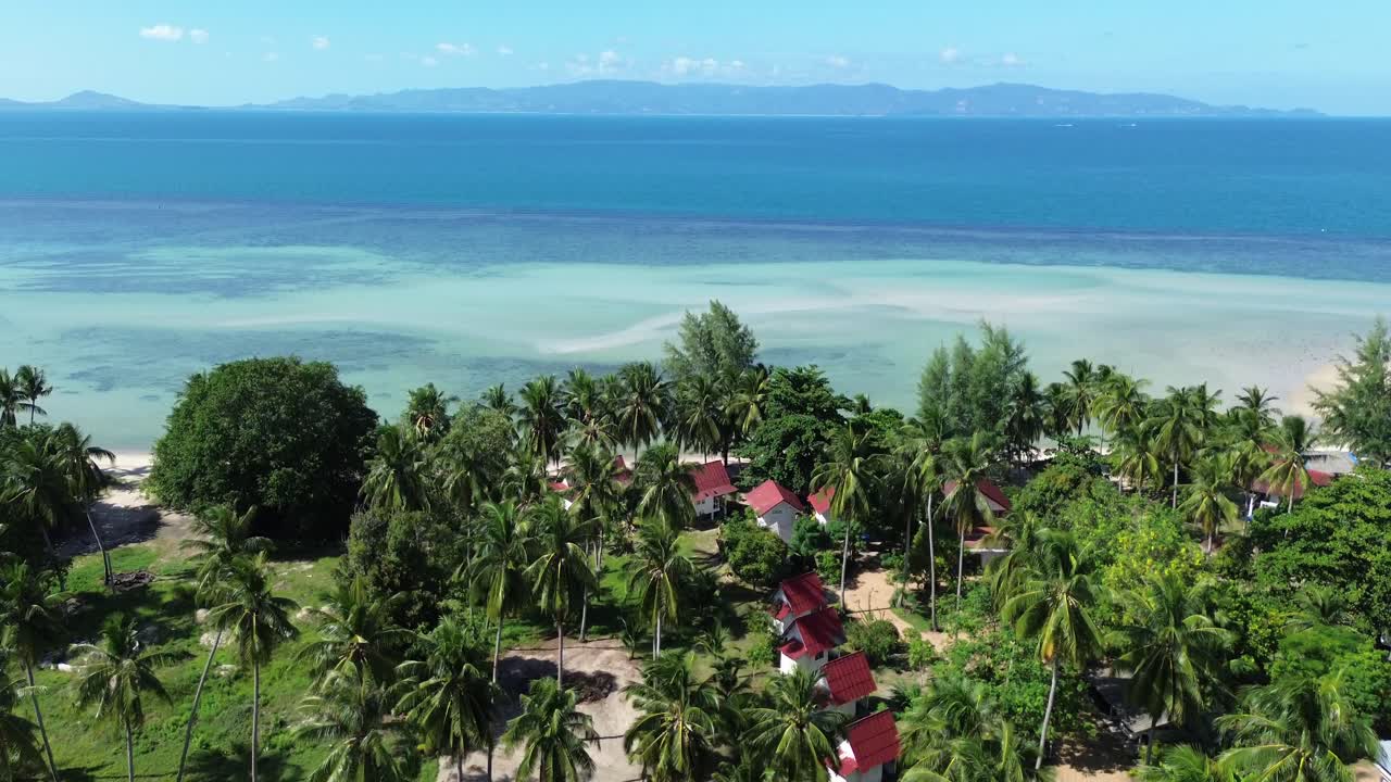 Stunning aerial drone footage flying over lush tropical palm trees, revealing turquoise sea, pristine sandy beaches and a scenic coastline, capturing paradise island views in Thailand