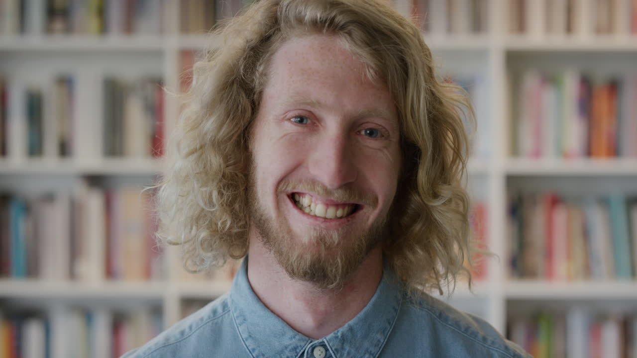retrato feliz joven hombre rubio estudiante sonriendo disfrutando de una educación exitosa estilo de vida independiente hombre caucásico en la biblioteca librería fondo cámara lenta