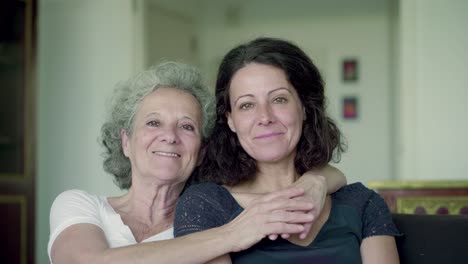 two happy women hugging and looking at camera.