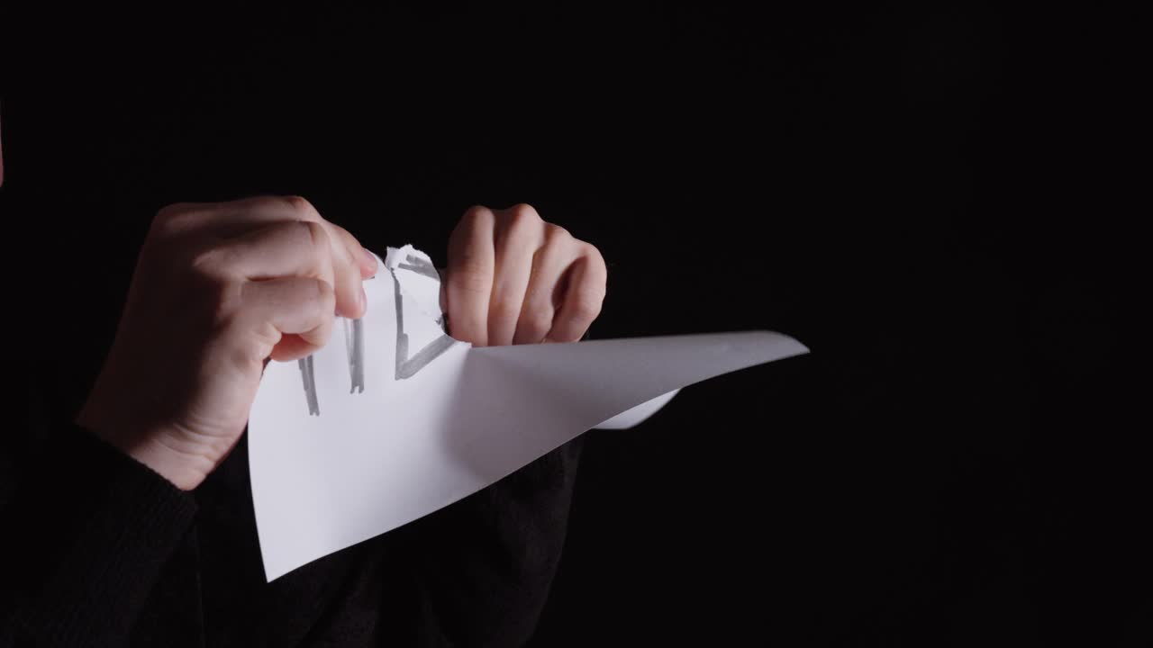 Hands tearing a “help” sign, symbolizing desperation, emotional crisis, and loss of hope