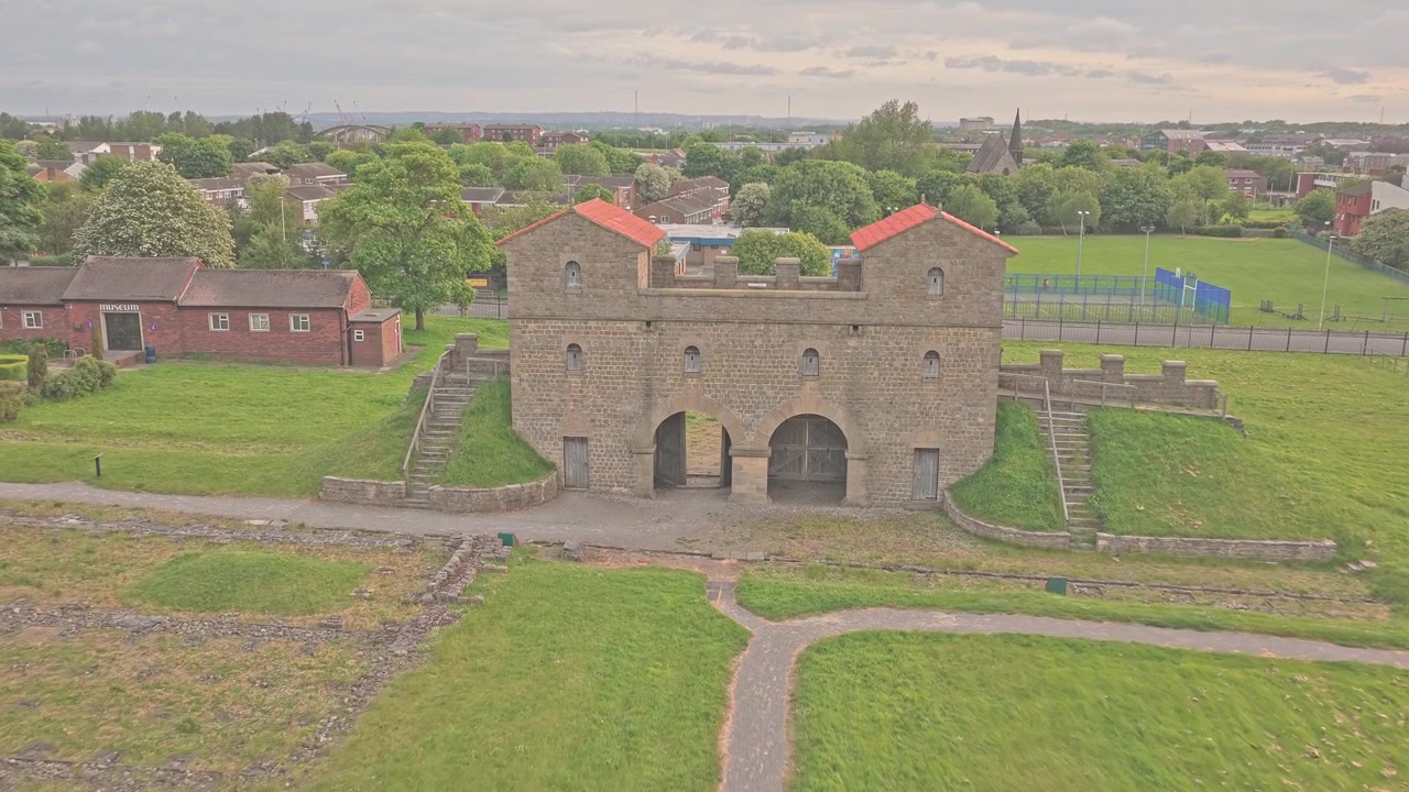 Il Forte Romano di Arbeia mostra la sua ricostruita porta romana sopra resti archeologici conservati e storiche mura difensive a South Shields, Tyne and Wear, Inghilterra, discesa in avanti del drone.