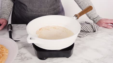 haciendo crepes en una sartén pequeña a fuego medio.