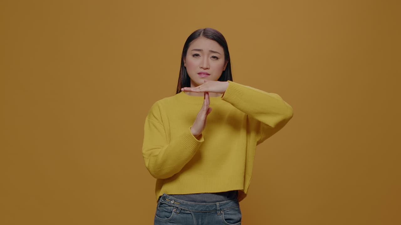 Tired woman doing timeout and break gesture in studio