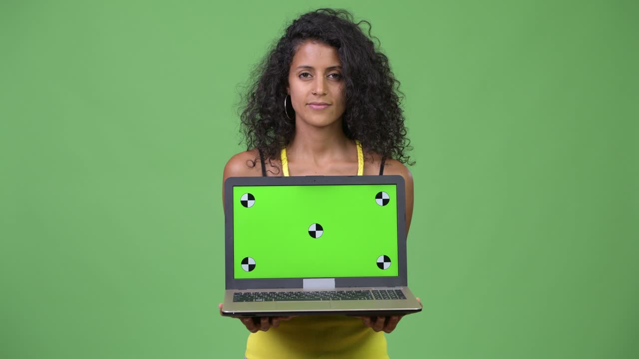 Young beautiful Hispanic woman showing laptop