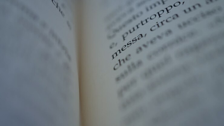 Camera scrolls across a page of an italian book slow motion macro shot shallow focus