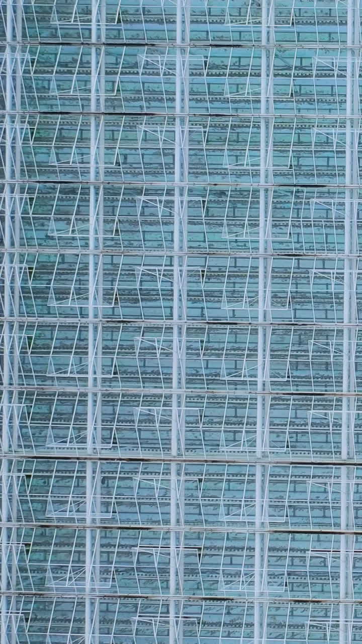 Aerial view of glass greenhouses. Metal frame construction with glass. Vertical video
