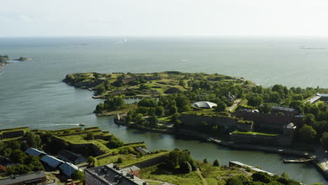 vista aerea di una barca che arriva al porto di varvilahti sull'isola della fortezza di suomenlinna, in una soleggiata giornata estiva, a helsinki, finlandia - orbita, colpo di drone